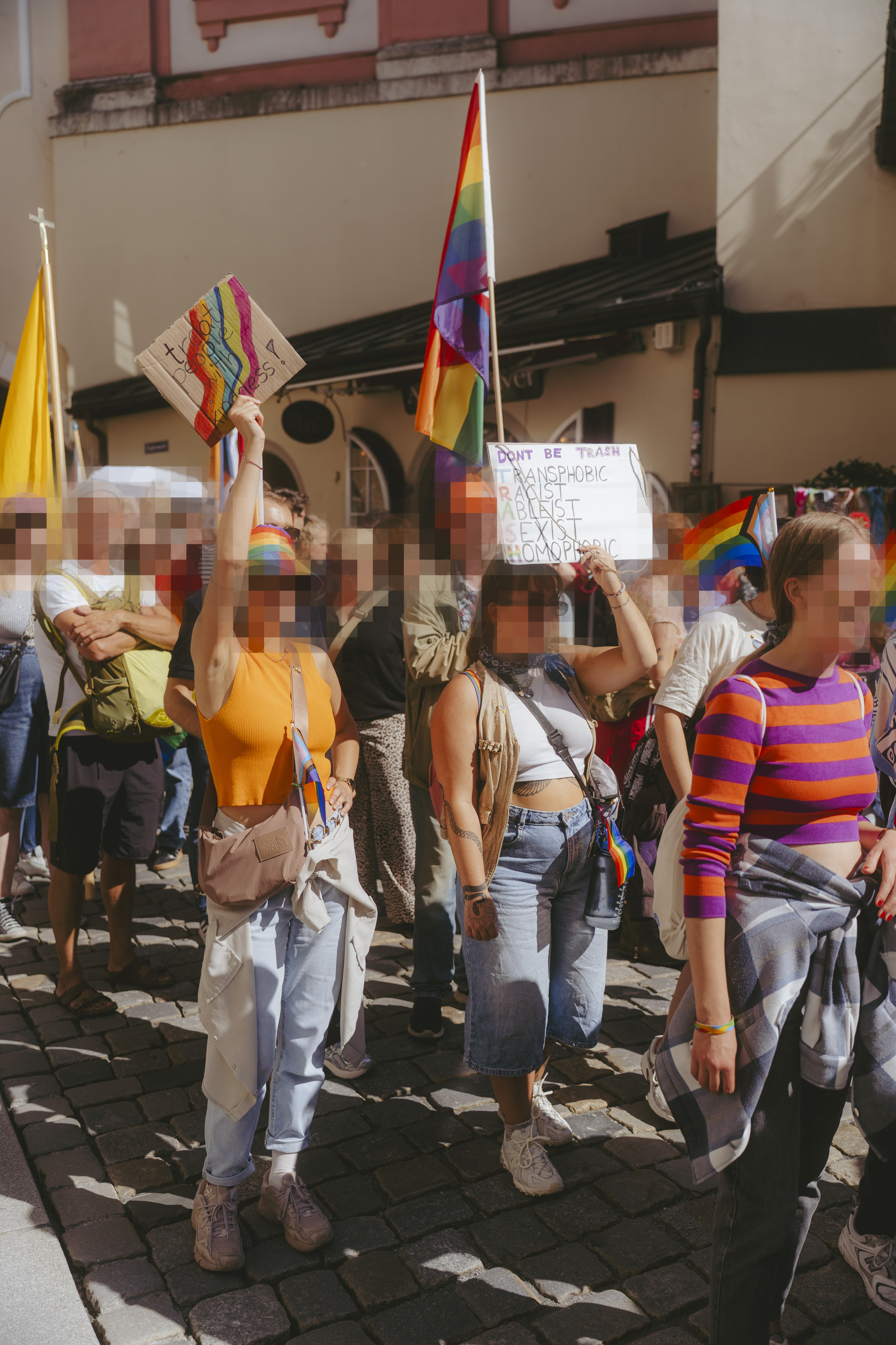 Mehrere Menschen auf dem CSD Demozug mt Flagen und Schildern.'.